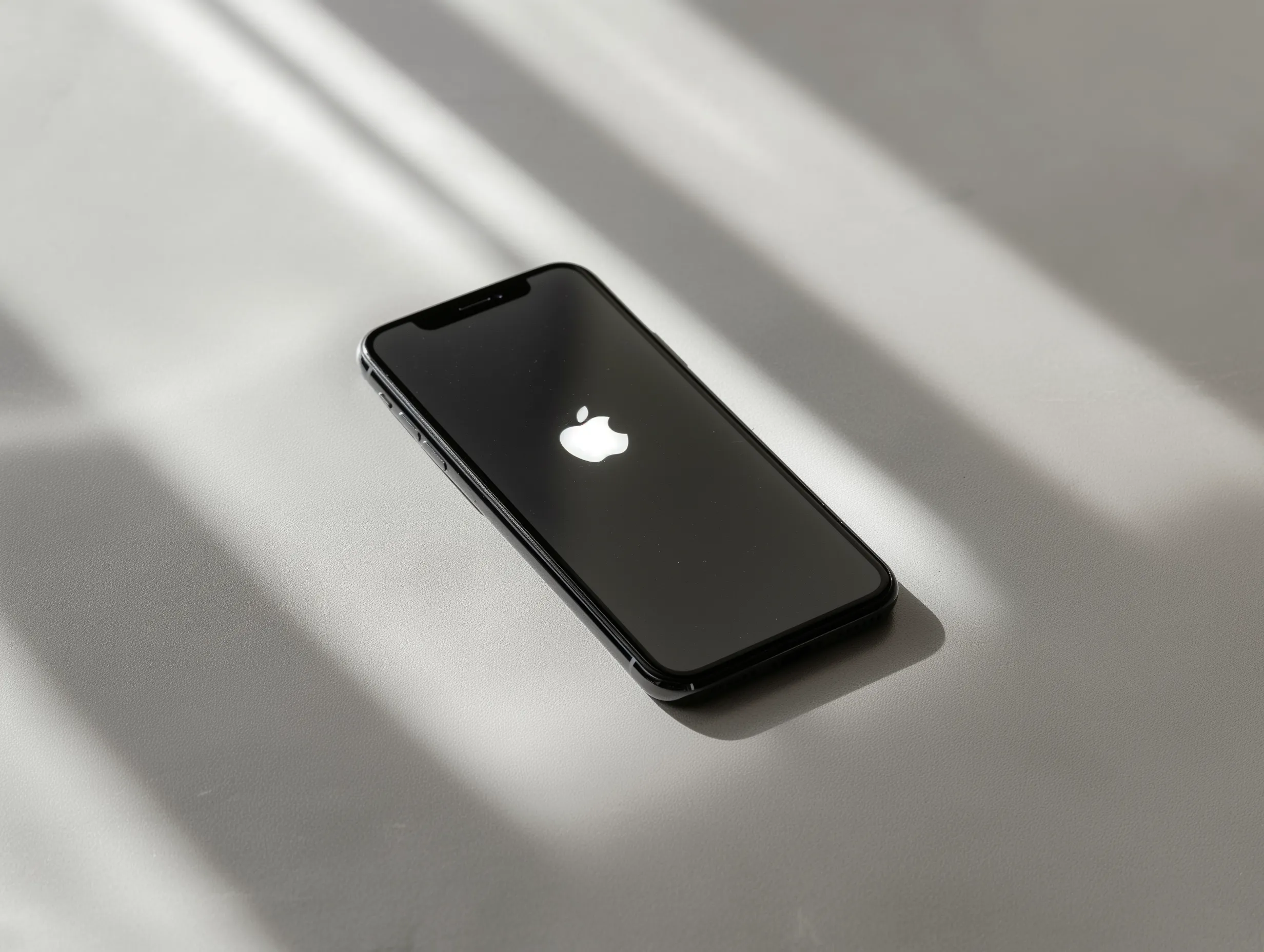 iPhone met Apple logo op lichtgrijs oppervlak